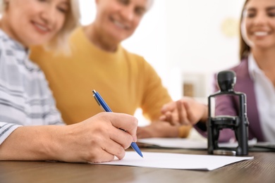 Mature couple signing document in notary's office, closeup