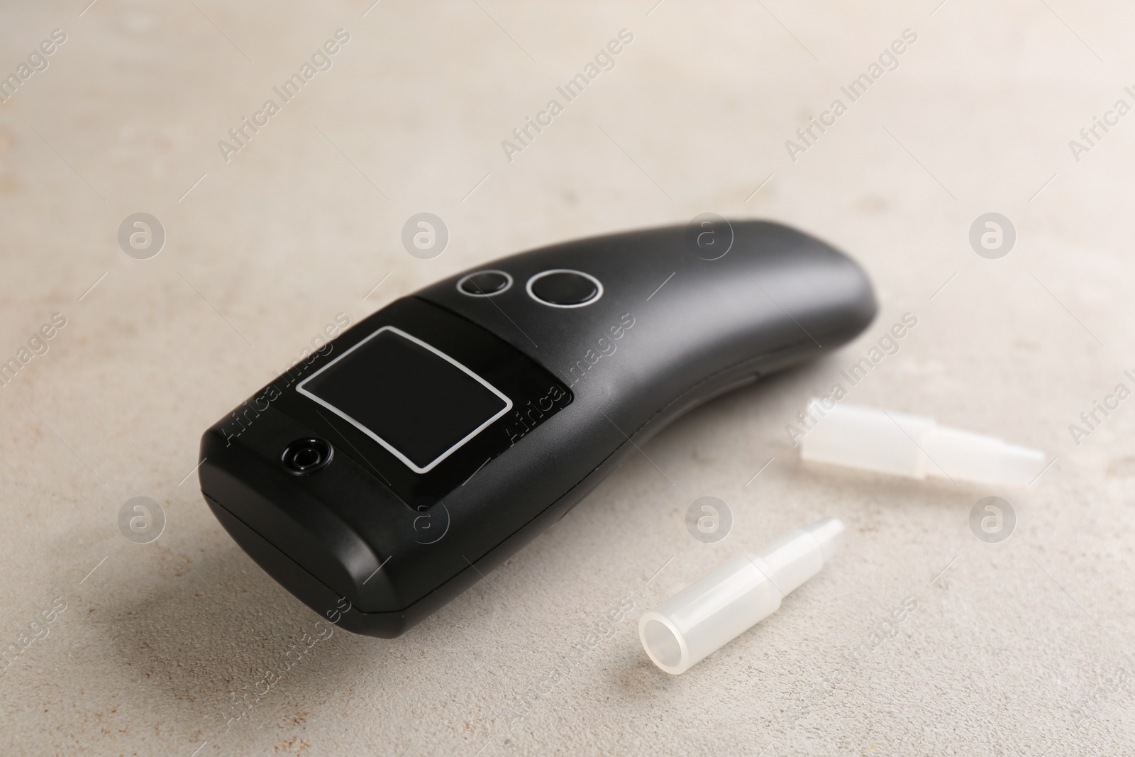 Photo of Modern breathalyzer with mouthpieces on light grey stone table