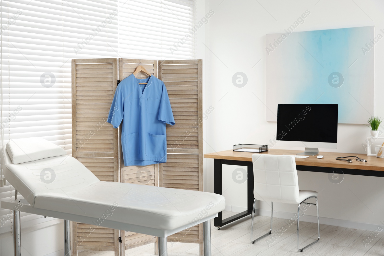 Photo of Modern medical office with doctor's workplace and examination table in clinic