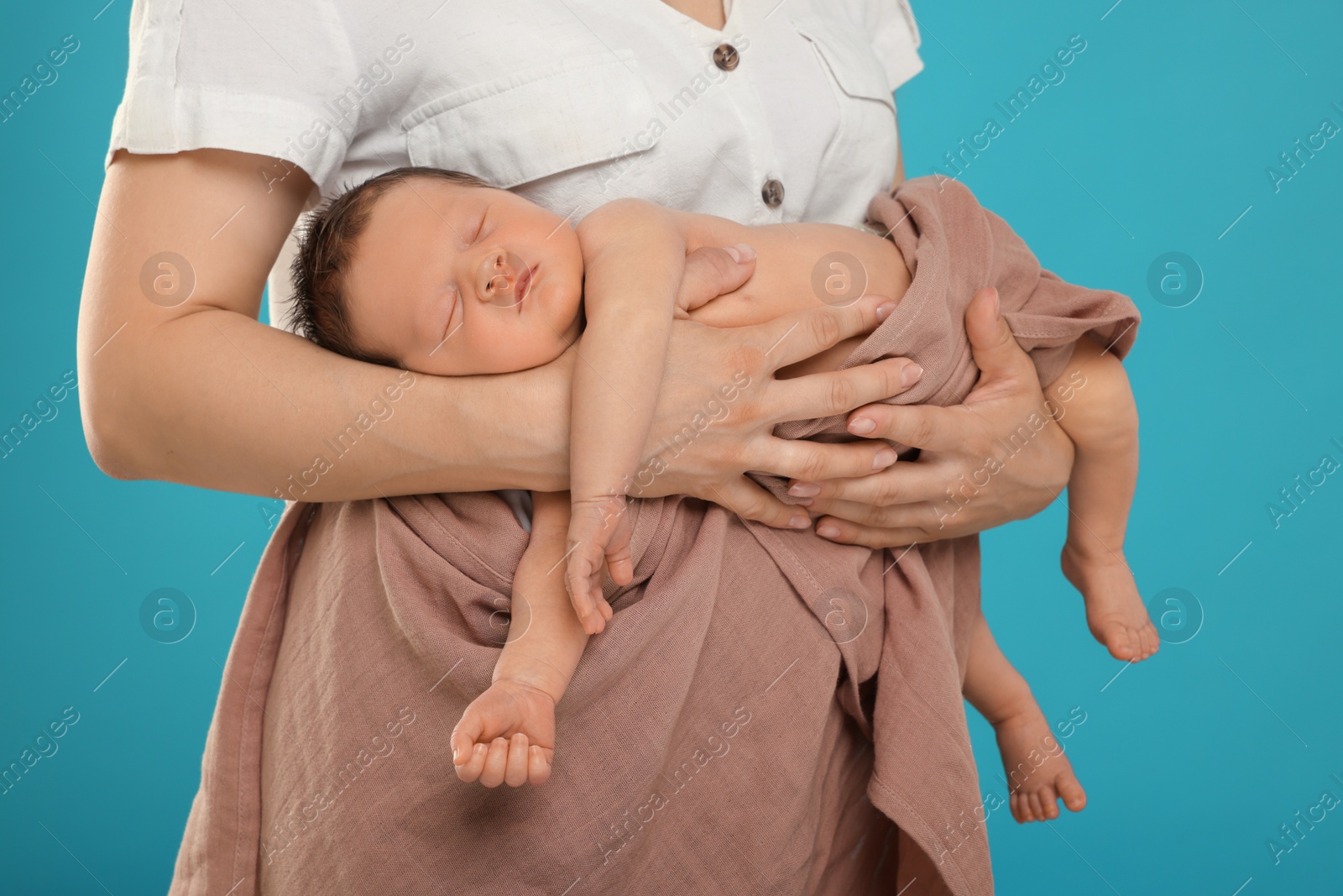 Photo of Mother with her cute newborn baby on light blue background, closeup