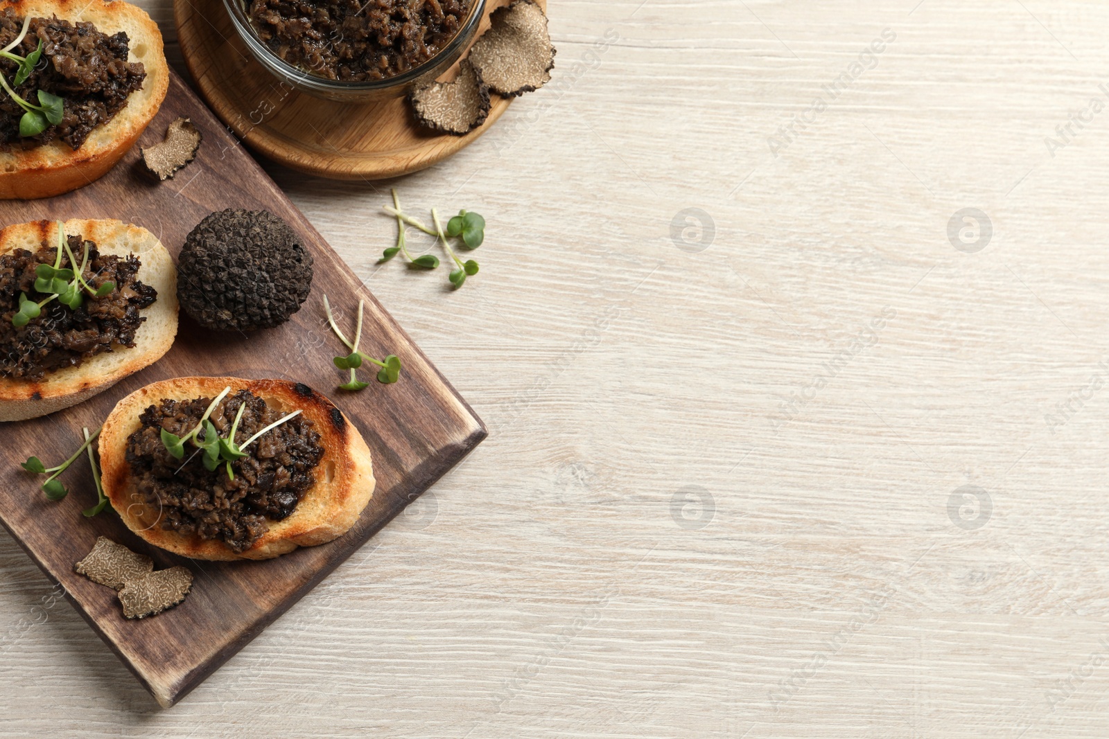 Photo of Delicious bruschettas with truffle sauce and microgreens on white wooden table, flat lay. Space for text