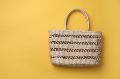 Photo of Stylish straw bag on yellow background, top view with space for text. Summer accessory