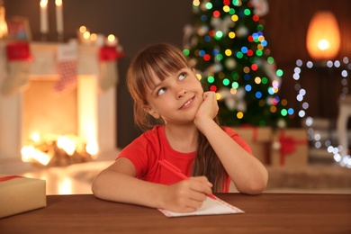 Photo of Little child writing letter to Santa at home. Christmas celebration