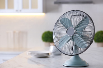 Photo of Modern electric fan on countertop in kitchen, space for text. Summer heat