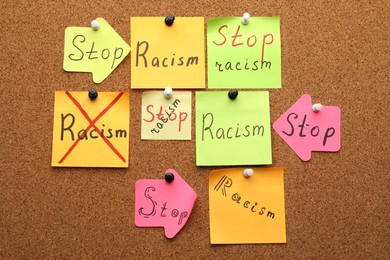 Paper notes with phrase Stop Racism pinned to cork board