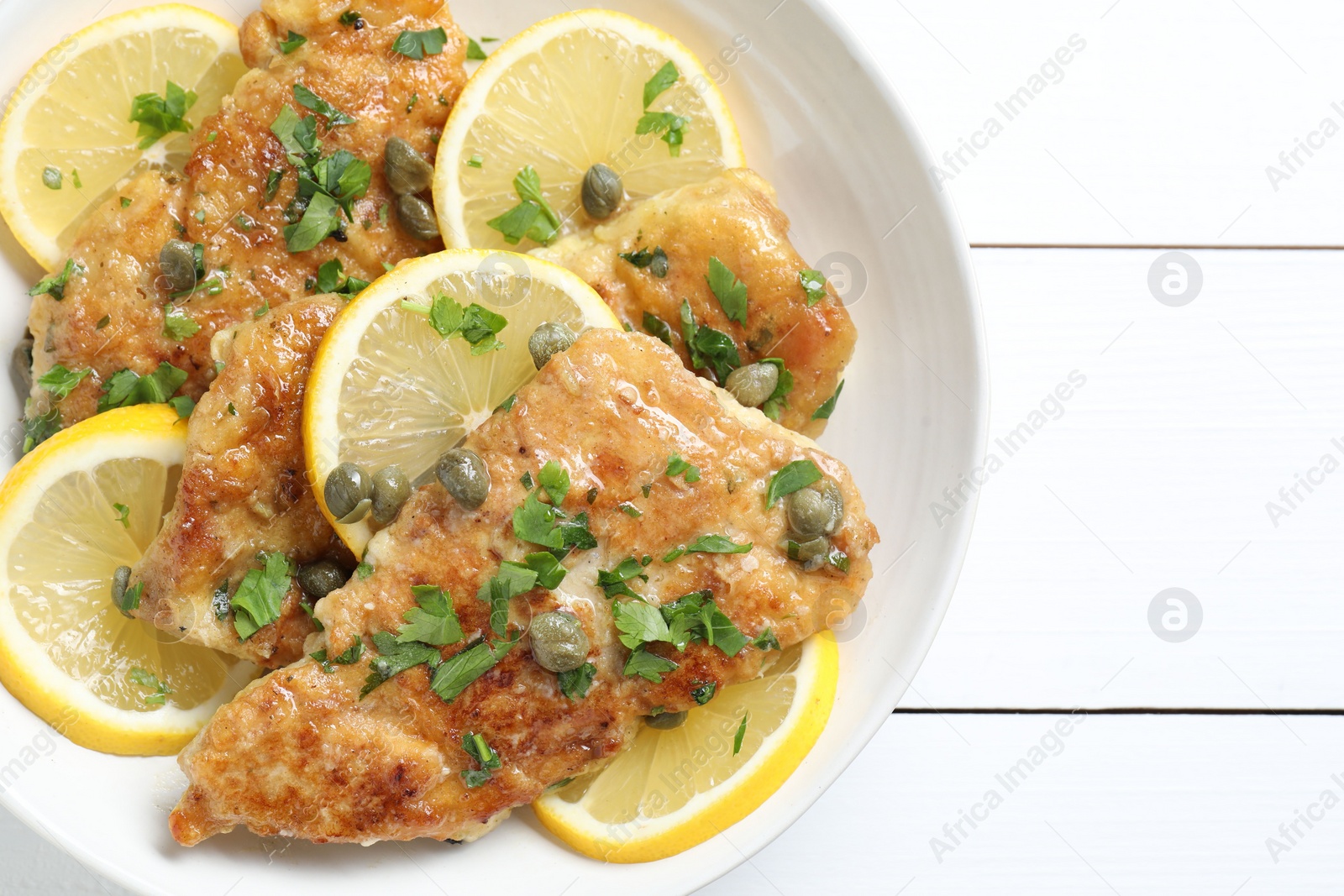 Photo of Delicious chicken piccata on white wooden table, top view