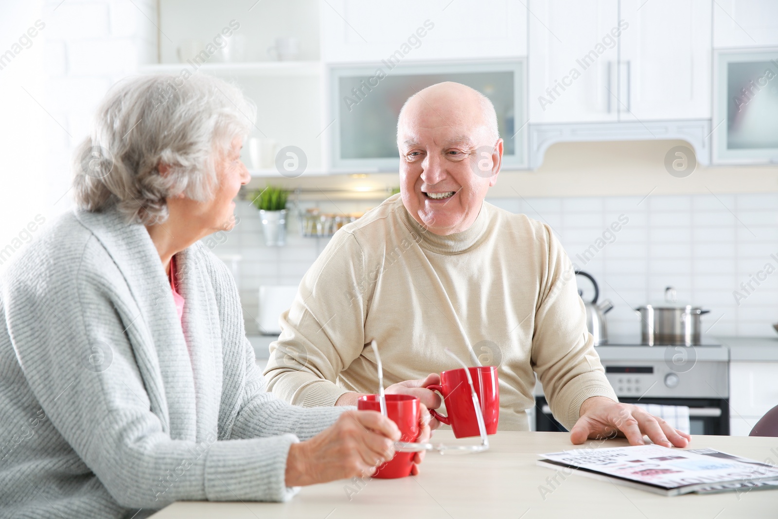 Photo of Elderly couple drinking tea at table in kitchen