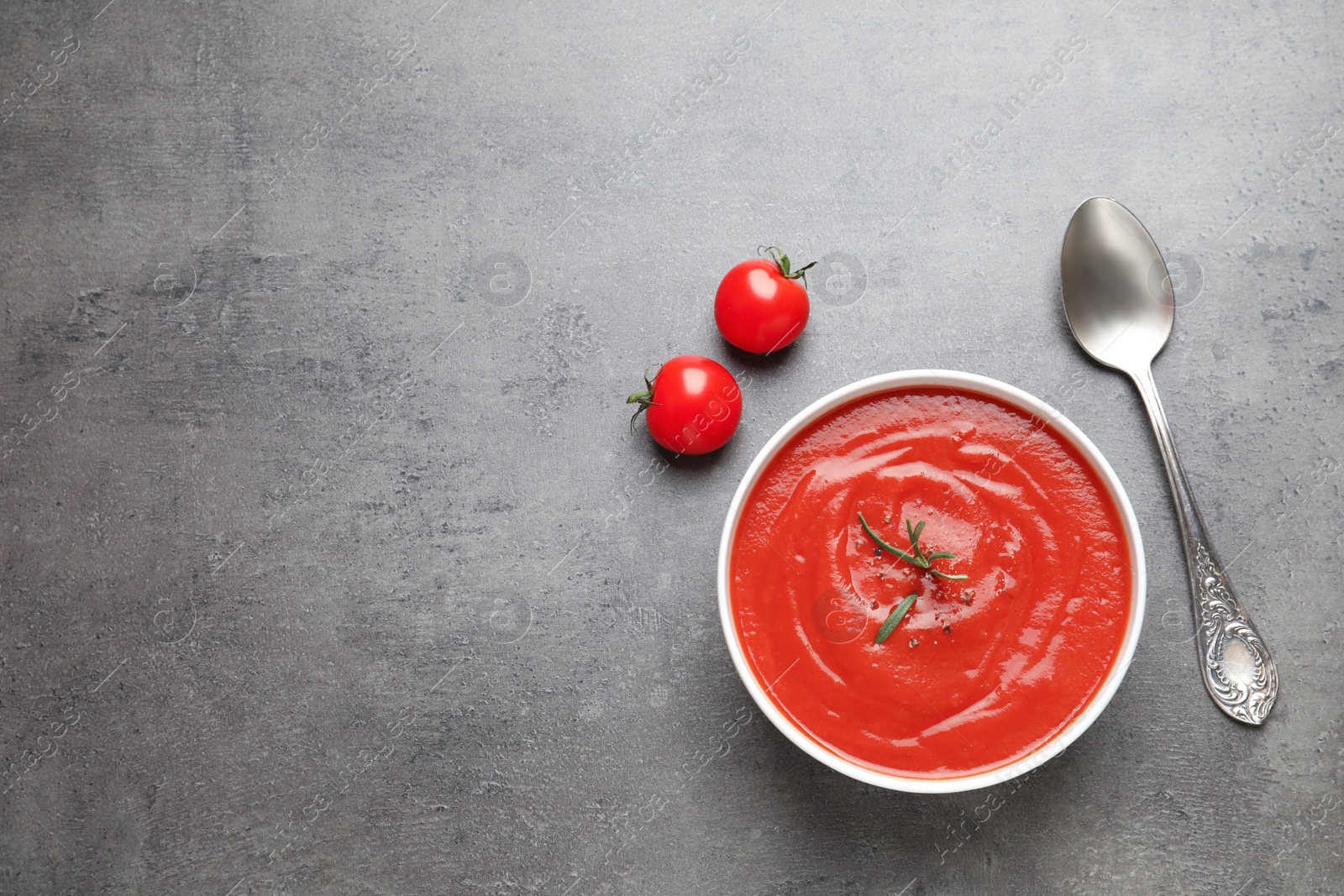 Photo of Bowl with fresh homemade tomato soup and space for text on grey background, top view