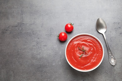 Bowl with fresh homemade tomato soup and space for text on grey background, top view