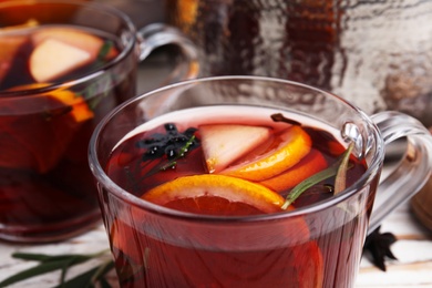 Photo of Tasty mulled wine with spices in glass cup on table, closeup