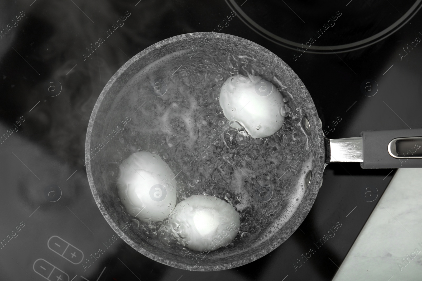 Photo of Boiling chicken eggs in saucepan on electric stove, top view