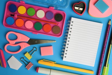 Flat lay composition with blank notebook and other school stationery on light blue background, space for text. Back to school