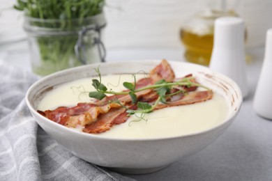 Photo of Delicious potato soup with bacon and microgreens on grey table, closeup