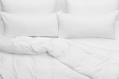 Photo of Soft white pillows and blanket on bed, top view