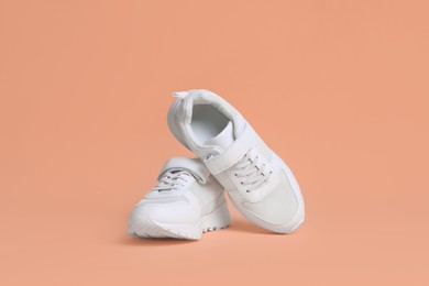 Photo of Pair of comfortable sports shoes on pale coral background