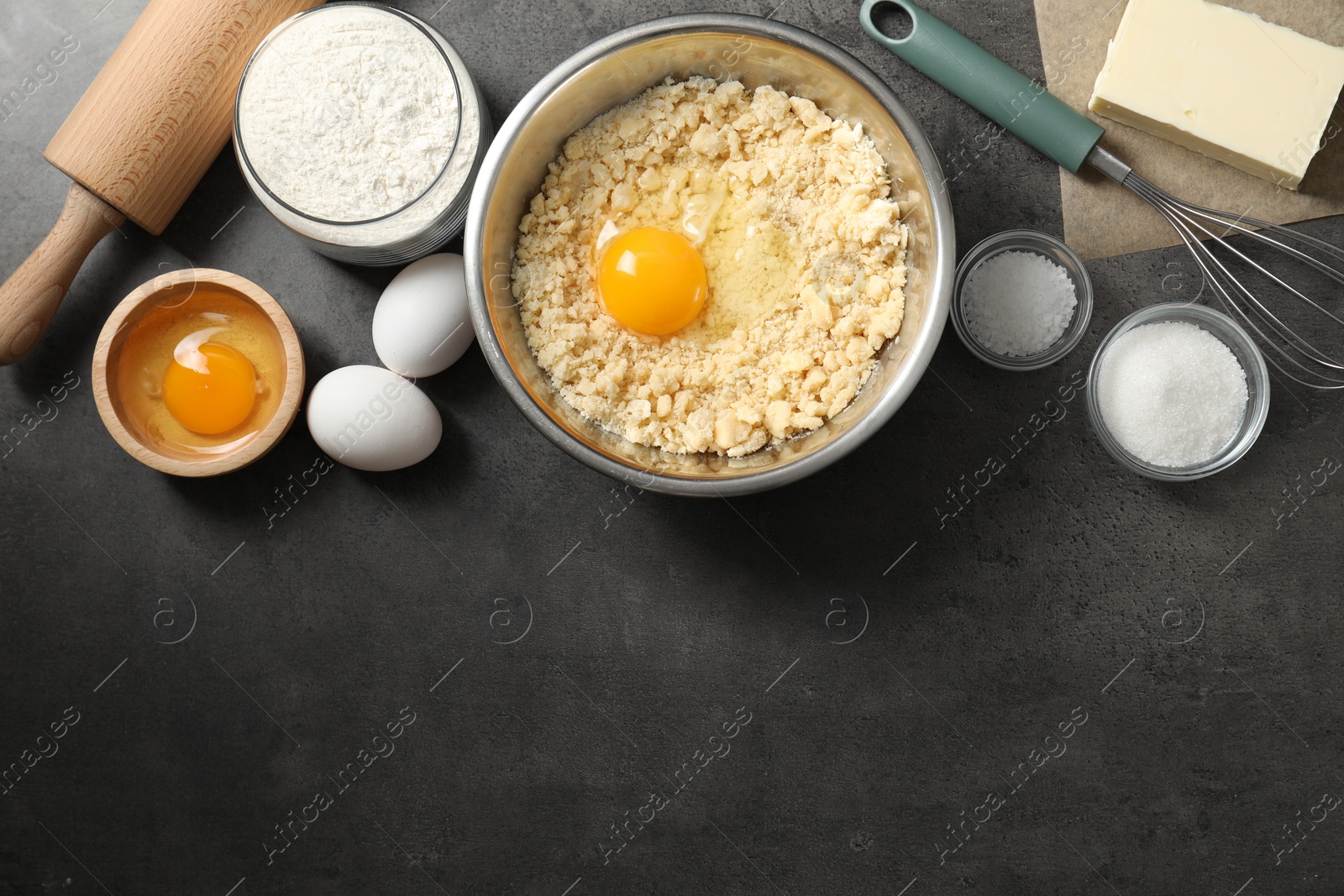 Photo of Making shortcrust pastry. Different ingredients for dough, rolling pin and whisk on grey table, flat lay. Space for text