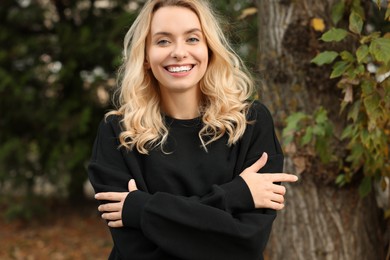 Photo of Happy woman in stylish warm sweater near tree outdoors