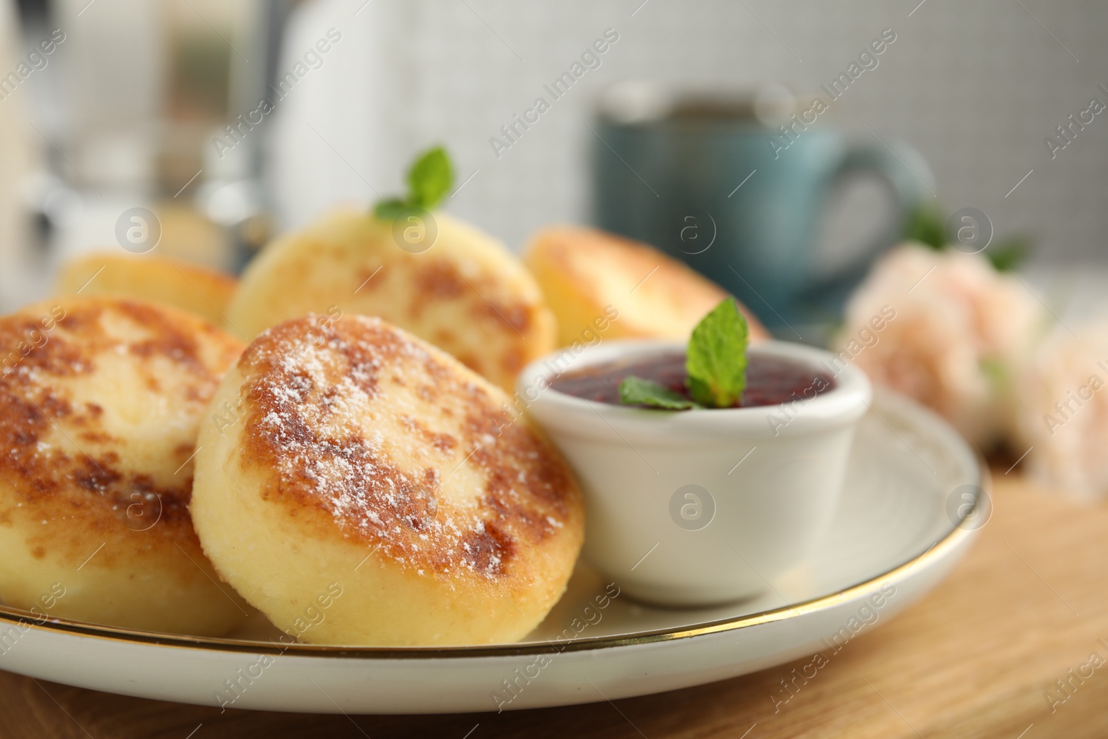 Photo of Delicious cottage cheese pancakes with jam, mint and icing sugar on wooden board, closeup