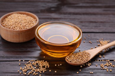 Photo of Bowl of natural oil and mustard seeds on wooden table
