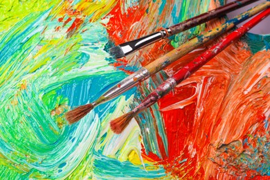 Closeup view of artist's palette with mixed paints and brushes as background