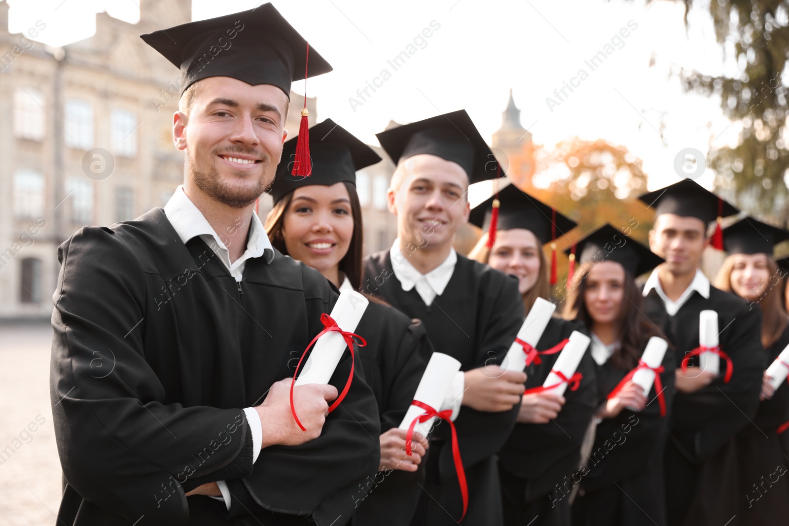 Photo of Happy students with diplomas outdoors. Graduation ceremony