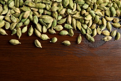 Photo of Dry cardamom pods on wooden table, top view. Space for text