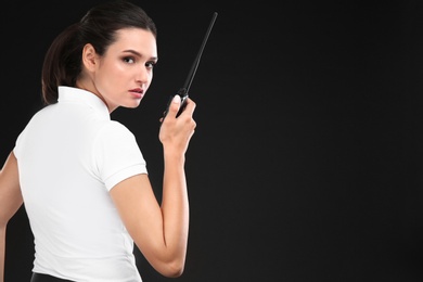 Female security guard using portable radio transmitter on dark background