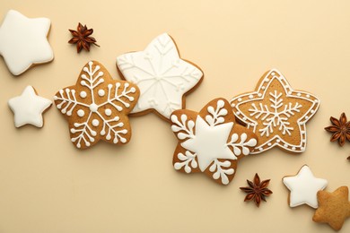 Photo of Tasty Christmas cookies with icing and anise stars on beige background, flat lay