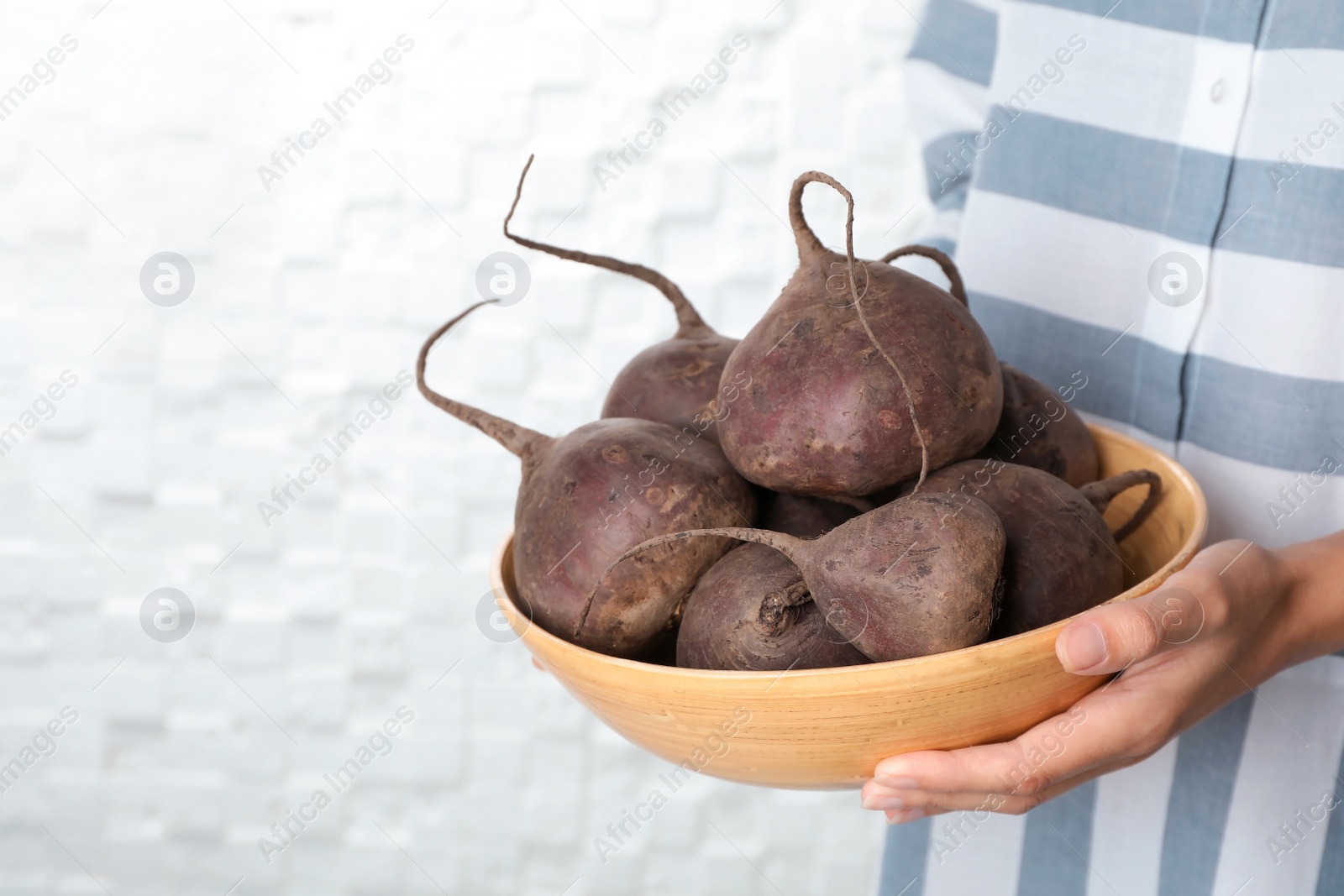 Photo of Woman holding bowl with beets on light background