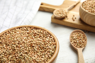 Uncooked green buckwheat grains on white wooden table, closeup