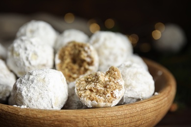 Photo of Tasty snowball cookies in wooden bowl, closeup. Christmas treat