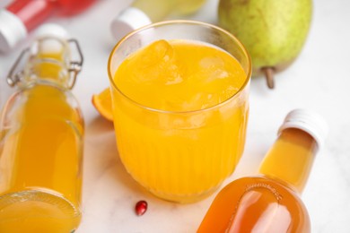 Photo of Tasty kombucha in glass and bottles on white table, closeup