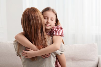 Cute daughter hugging her mom at home. Space for text
