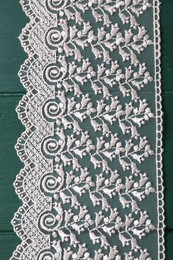 Photo of Beige lace on green wooden table, top view