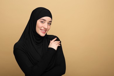 Portrait of Muslim woman in hijab on beige background. Space for text