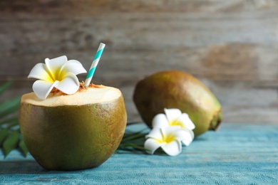 Photo of Fresh green coconut with drinking straw on wooden table