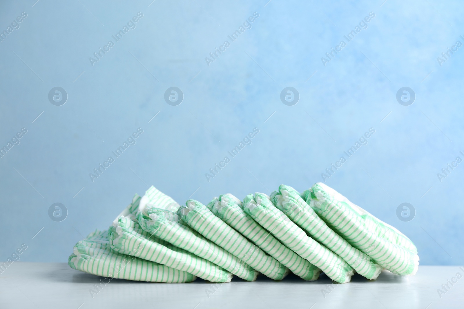 Photo of Disposable diapers on table against color background, space for text. Baby accessories