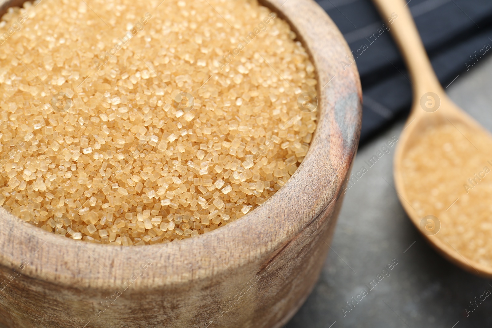 Photo of Brown sugar in bowl on grey table, closeup