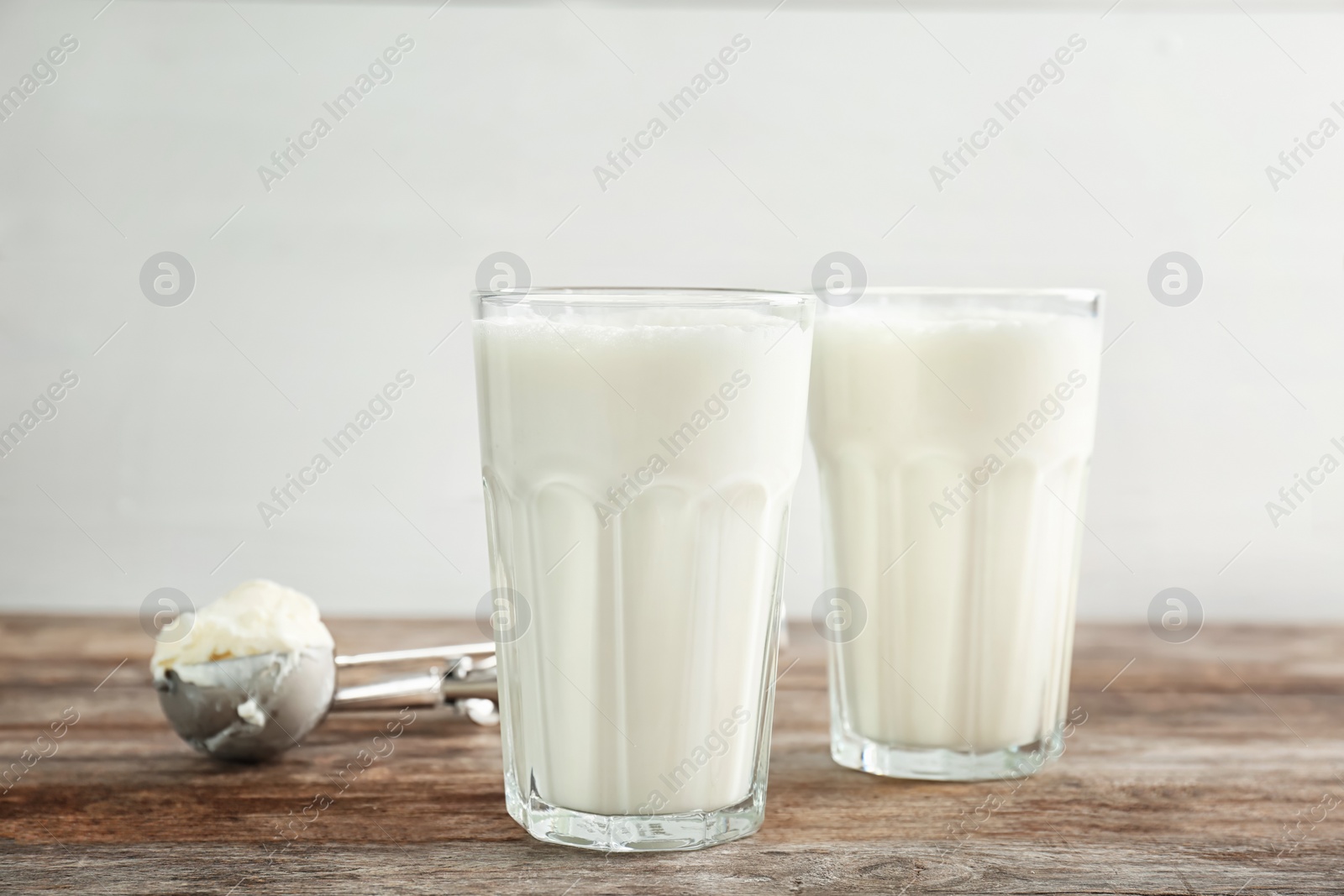 Photo of Glasses with milkshake and tasty vanilla ice cream on wooden table