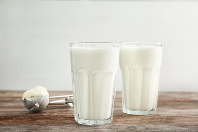 Glasses with milkshake and tasty vanilla ice cream on wooden table