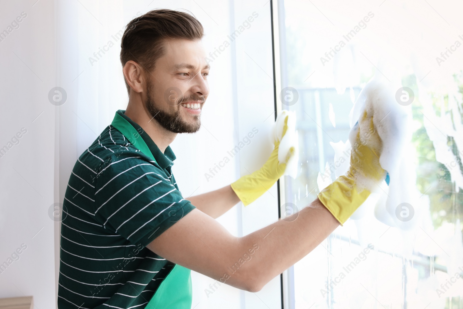 Photo of Male worker washing window glass at home