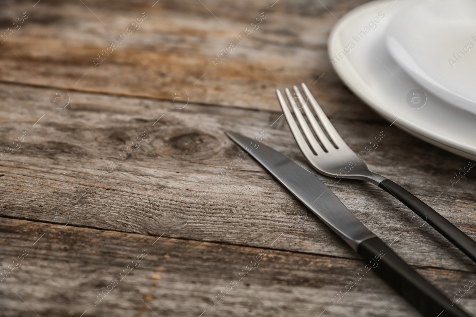 Photo of Empty dishware and cutlery on wooden table, close up view. Table setting