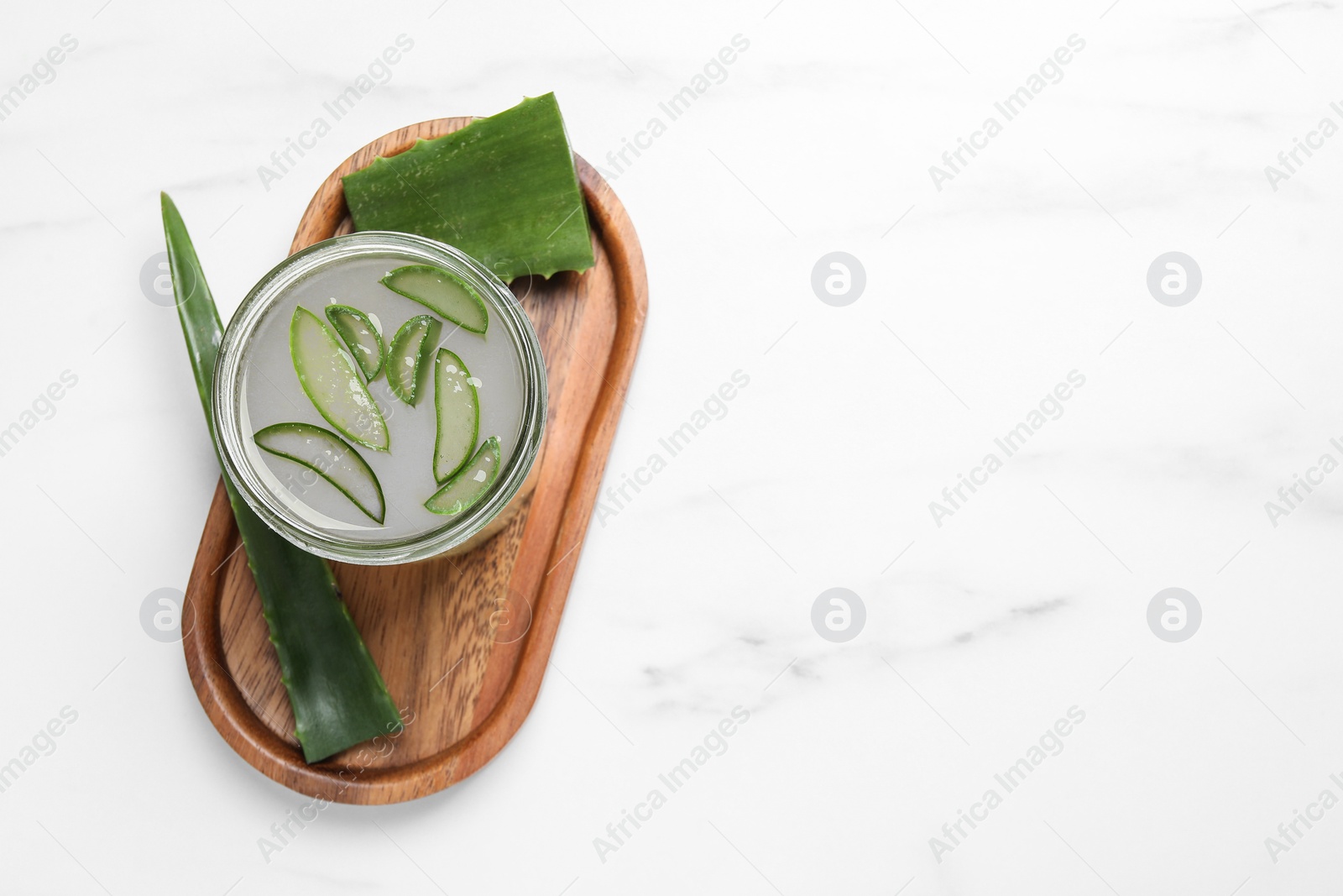 Photo of Fresh aloe juice in jar and leaves on white marble table, top view. Space for text