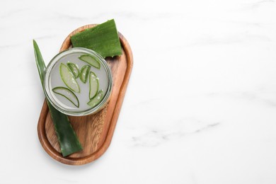 Photo of Fresh aloe juice in jar and leaves on white marble table, top view. Space for text