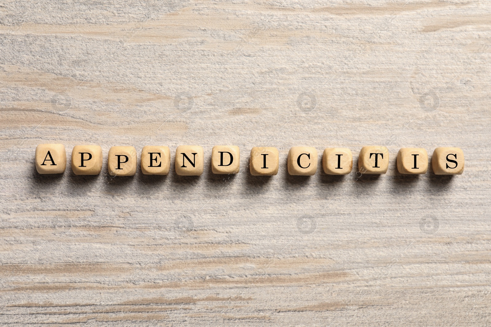 Photo of Word Appendicitis made of cubes with letters on wooden table, top view