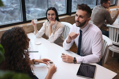 Photo of Group of coworkers having coffee break in cafe