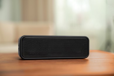 Photo of One black portable bluetooth speaker on wooden table indoors. Audio equipment