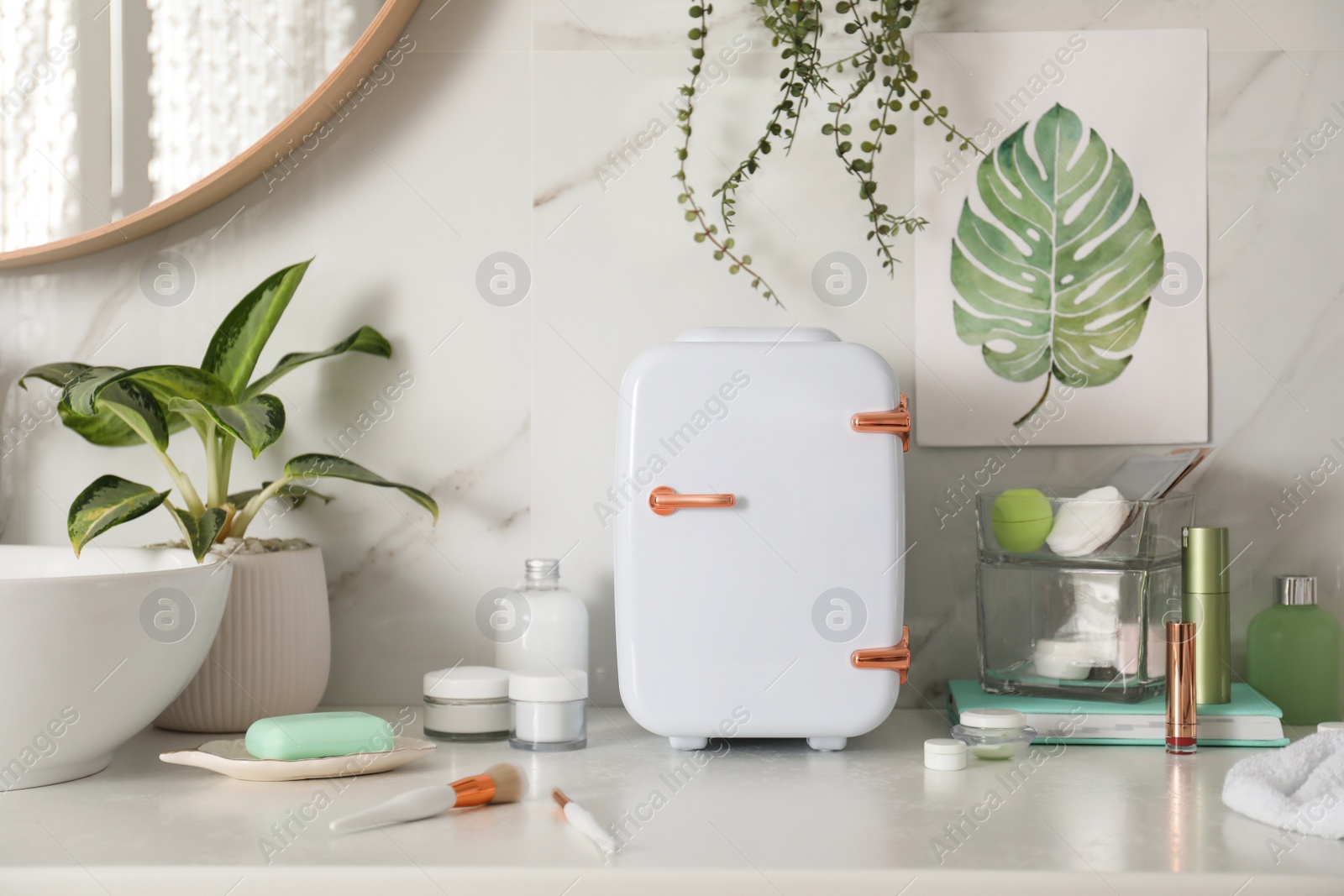 Photo of Cosmetics refrigerator and skin care products on white countertop in bathroom