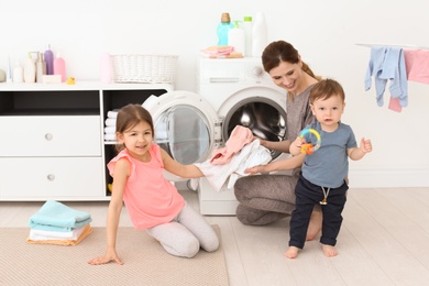 Housewife with little children doing laundry at home