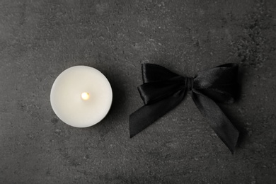 Photo of Black ribbon and candle on grey background, top view. Funeral symbols